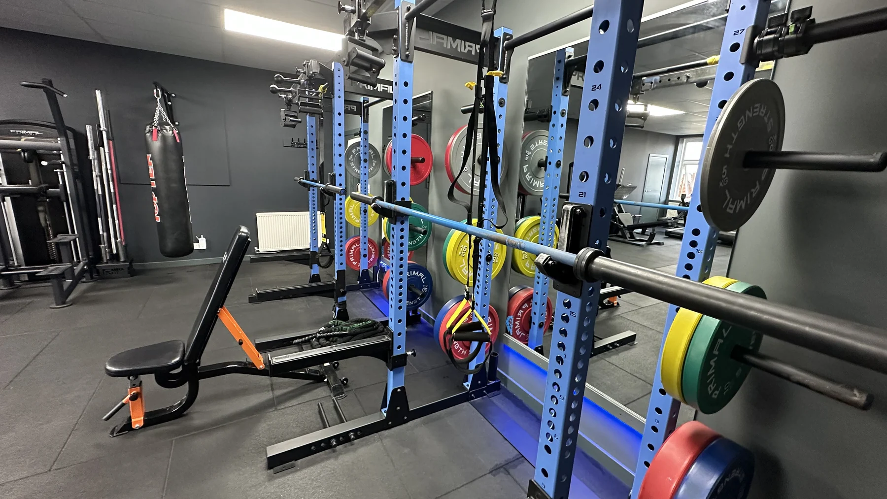 Blue strength racks, barbells, weight plates and suspension straps at Braveheart