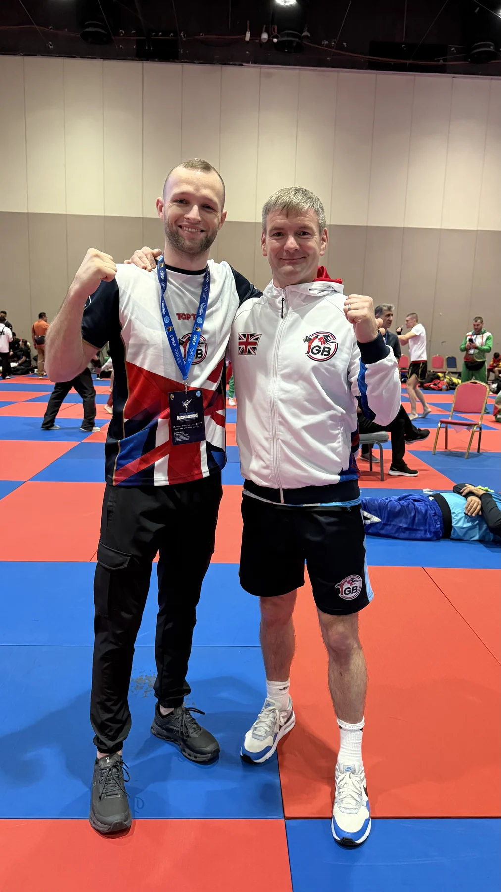 Two members of the Kickboxing GB team together beside the competition mats